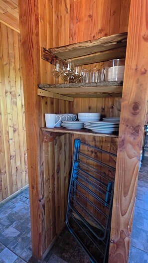 A wooden interior with shelves holding glassware and plates.