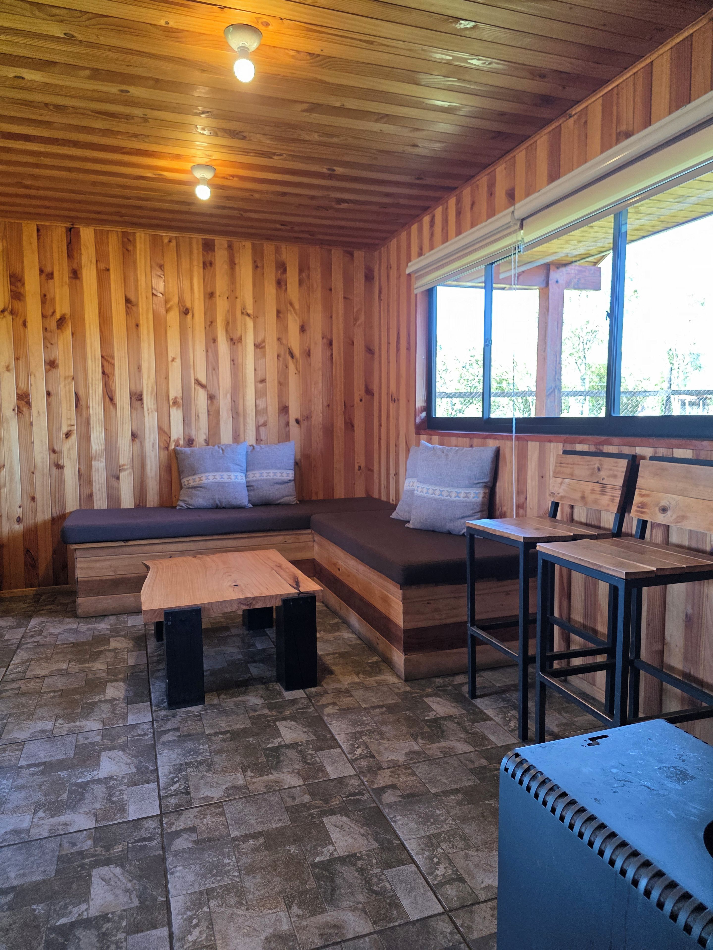 A wooden interior with a built-in bench and a small table.