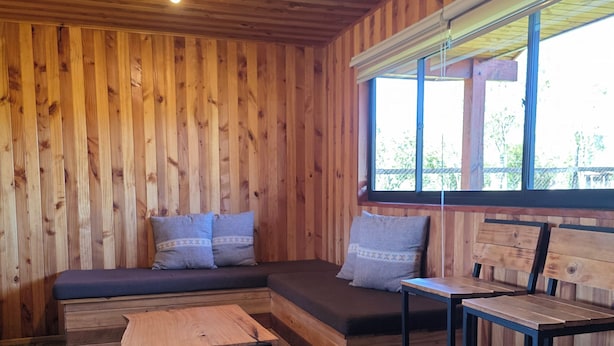 A wooden interior with a built-in bench and a small table.