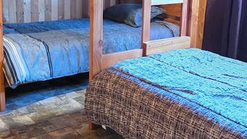 A room with two bunk beds, wooden walls, and a tiled floor.