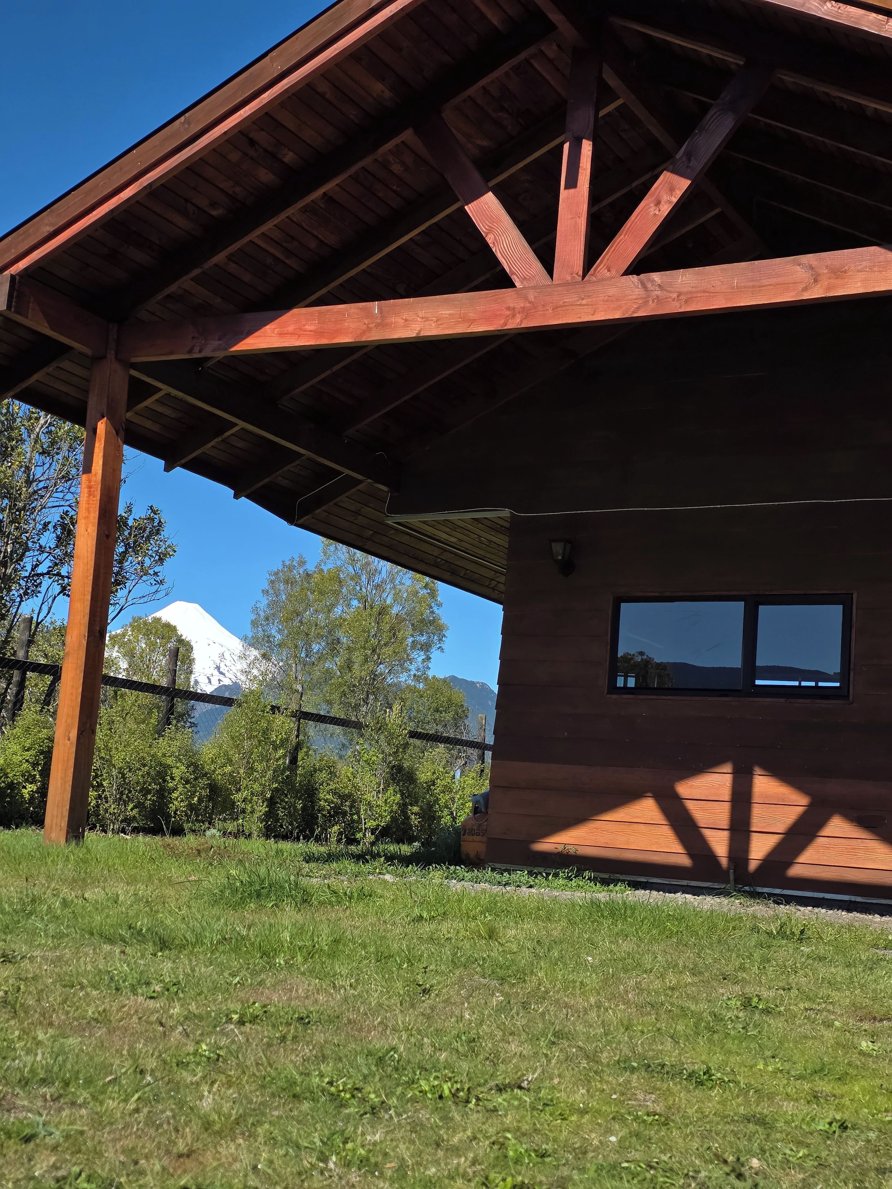A wooden building with a sloped roof, a window, and a view of a mountain.