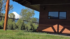 A wooden building with a sloped roof, a window, and a view of a mountain.