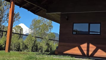 A wooden building with a sloped roof, a window, and a view of a mountain.