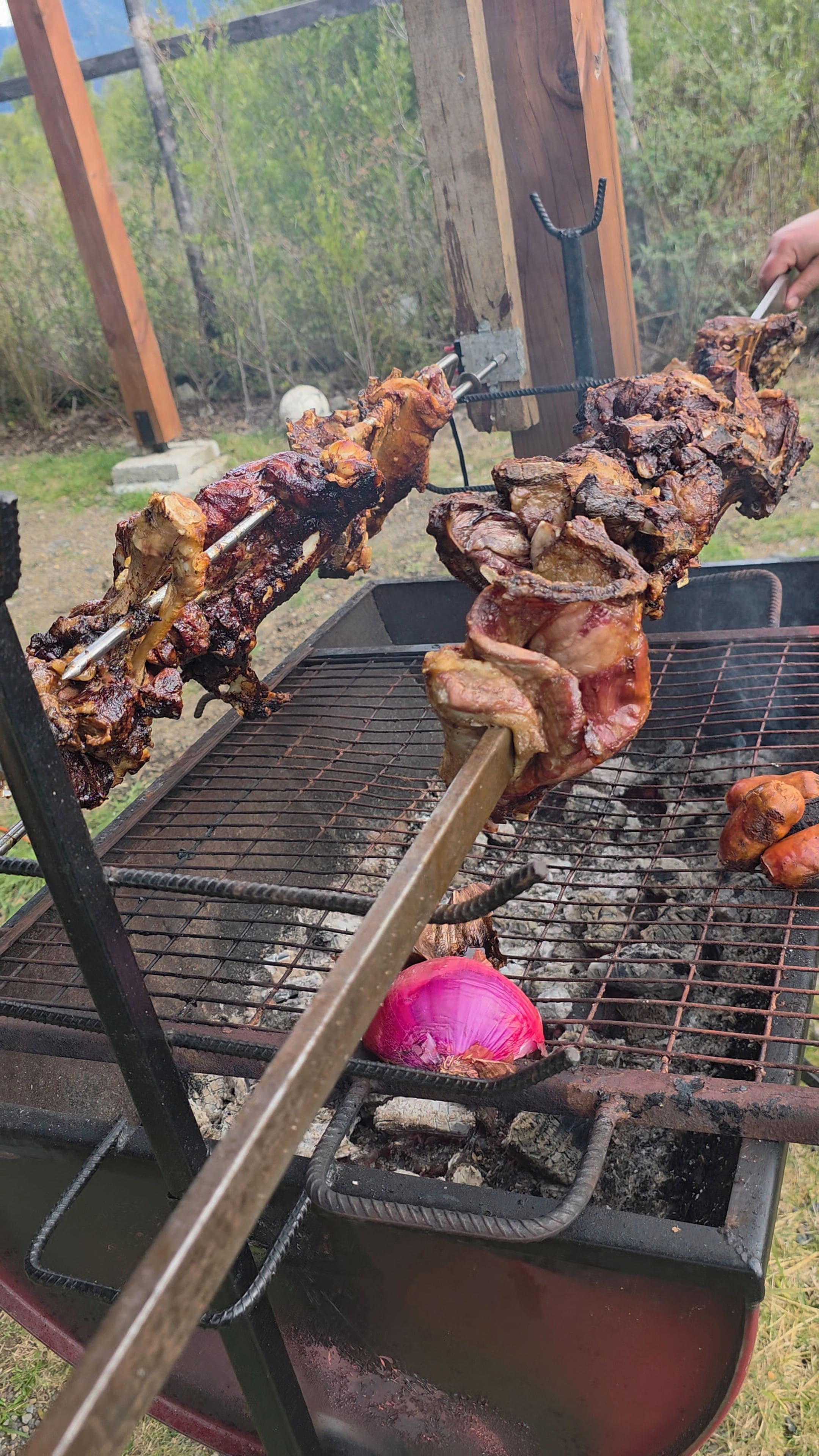 A barbecue grill with skewers of meat and a whole onion.