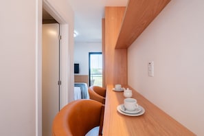 Ein modernes Hotelzimmer mit einem Holztisch, zwei Stühlen, einem Bett und einem Fernseher.