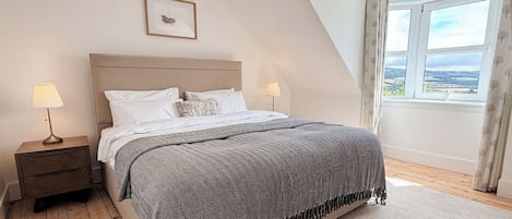 A bedroom with a bed, nightstands, a window with a view, and a framed picture on the wall.