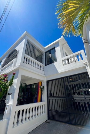 A two-story building with a white exterior, large windows, and a black gate. - 4-bedroom apartment 1 block from Ocean Park Beach (San Juan)
