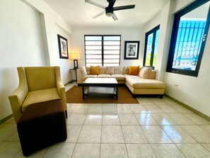 Una sala de estar con sofá, sillón, mesa de centro y ventilador de techo.