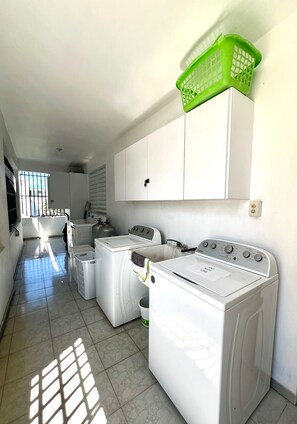 A laundry room with white appliances, a green basket, and a window allowing natural light. - 4-bedroom apartment 1 block from Ocean Park Beach (San Juan)