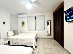 A hotel room with two beds, a flat-screen TV mounted on the wall, a ceiling fan, and a large mirror. - 4-bedroom apartment 1 block from Ocean Park Beach (San Juan)