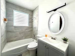 Un baño con bañera, inodoro, lavabo y espejo.