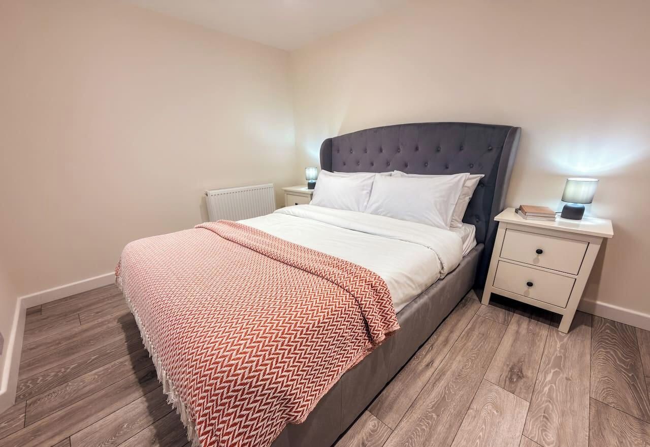 A bedroom with a bed, bedside tables, and a radiator.