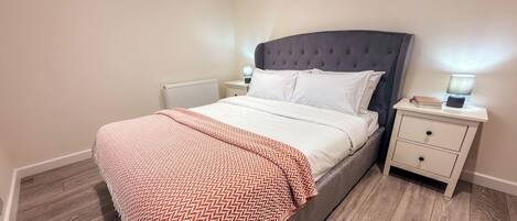 A bedroom with a bed, bedside tables, and a radiator.