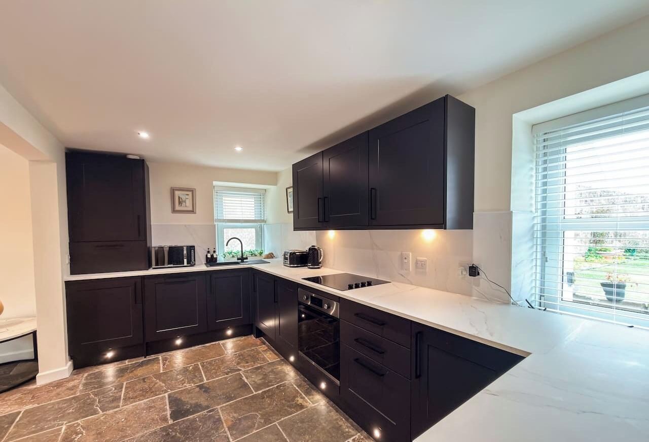 A modern kitchen with dark cabinetry, a white countertop, and a built-in oven.
