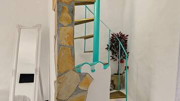 Eine Treppe mit einer Steinsäule, einem türkisblauen Geländer und einem Blumentopf.