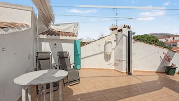 Eine Dachterrasse mit Tisch und Stühlen, einem Blumentopf und einem Warmwasserbereiter.