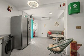 Una cucina moderna con frigorifero in acciaio inox, lavatrice e zona pranzo con tavolo e sedie rotonde.