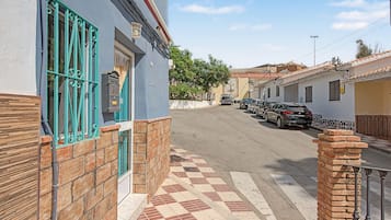Una vista di una strada con auto parcheggiate, un edificio con facciata blu e un marciapiede in lastre.