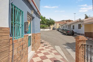 Una vista di una strada con auto parcheggiate, un edificio con facciata blu e un marciapiede in lastre.