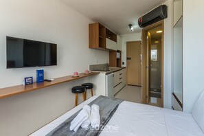 Et lille hotelværelse med seng, fjernsyn, tekøkken og badeværelse.