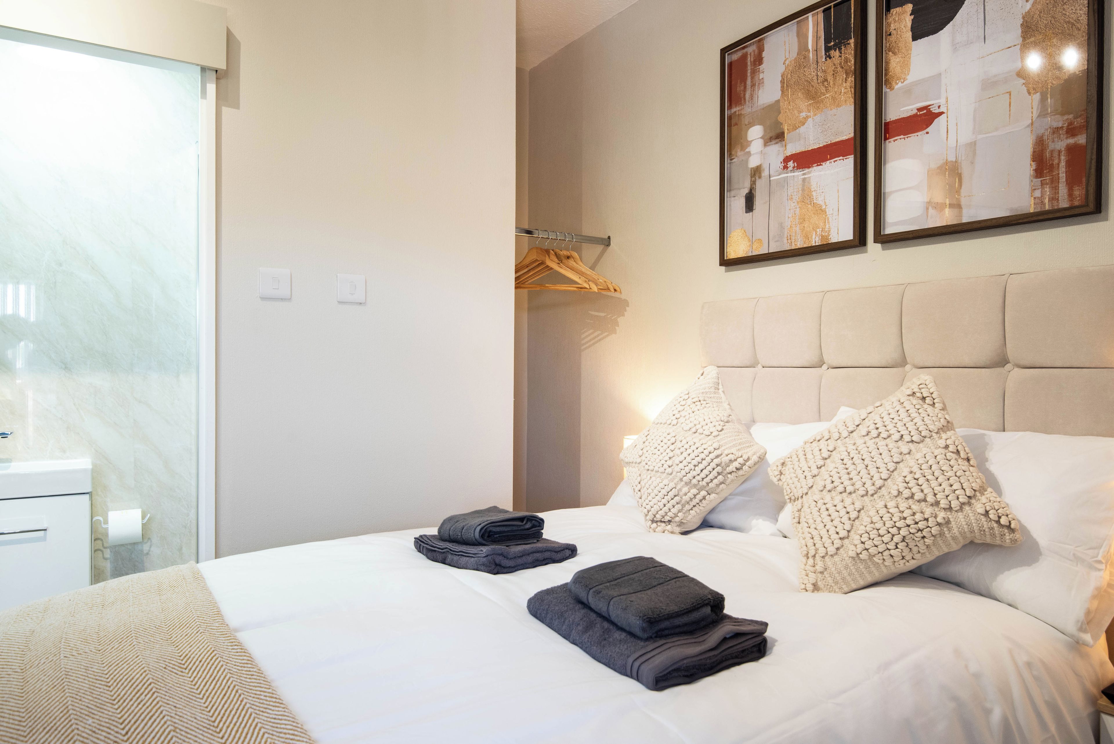 Une chambre d’hôtel comprenant un lit, une table de chevet, une armoire et une œuvre d’art encadrée accrochée au mur.
