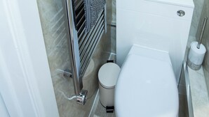 Ein modernes Badezimmer mit Toilette, Handtuchhalter, Toilettenpapierhalter und Heizkörper.