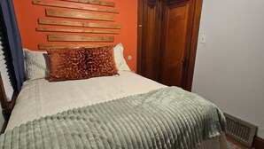 Een slaapkamer met een bed, een houten hoofdbord, een deur en een radiator.