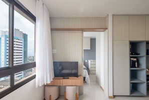Ein modernes Hotelzimmer mit großem Fenster, Schreibtisch mit Stuhl, Bett und Kleiderschrank.