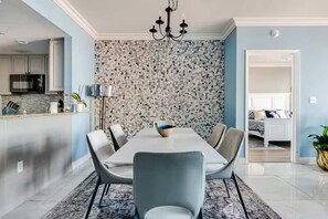 A dining area with a table, chairs, and a chandelier. - Ocean Front Condo w/ Pools, Sauna, Tennis & Gym (Escambia County)
