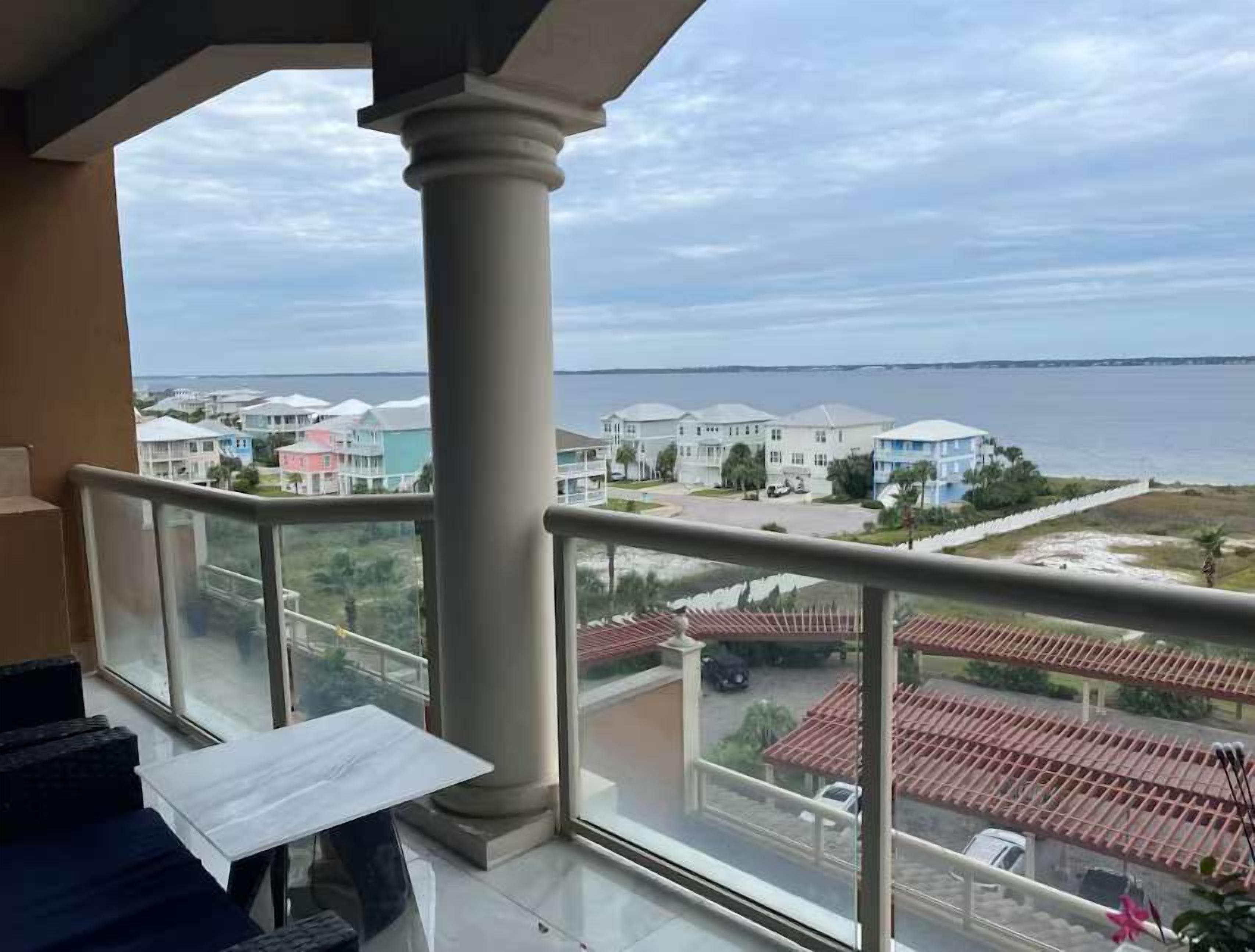 A balcony with a view of a residential area and a body of water.