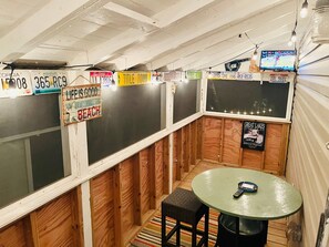 Ein Zimmer mit Holzvertäfelung, einem runden Tisch und einem Fernseher, sowie verschiedene Nummernschilder an den Wänden.