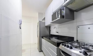 Una cocina moderna con azulejos blancos, electrodomésticos de acero inoxidable y una estufa a gas.