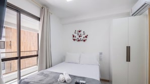 A hotel room with a bed, a wall-mounted artwork, a wardrobe, and a window with curtains. - Apt in Condo w/ Pool in Federacao Hfo1006 (Salvador)