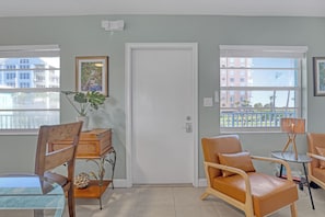 A room with a door, two windows, a plant, a table, and two chairs. - OUTSTANDING Location!  High-end 2/1 On The Beach, Close To The Port & Pier! (Cocoa Beach)