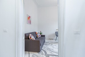 A modern living room with a grey sofa, colorful cushions, a marble-patterned floor, and a minimalist decor. - Authentic Prati Penthouse (Rome)