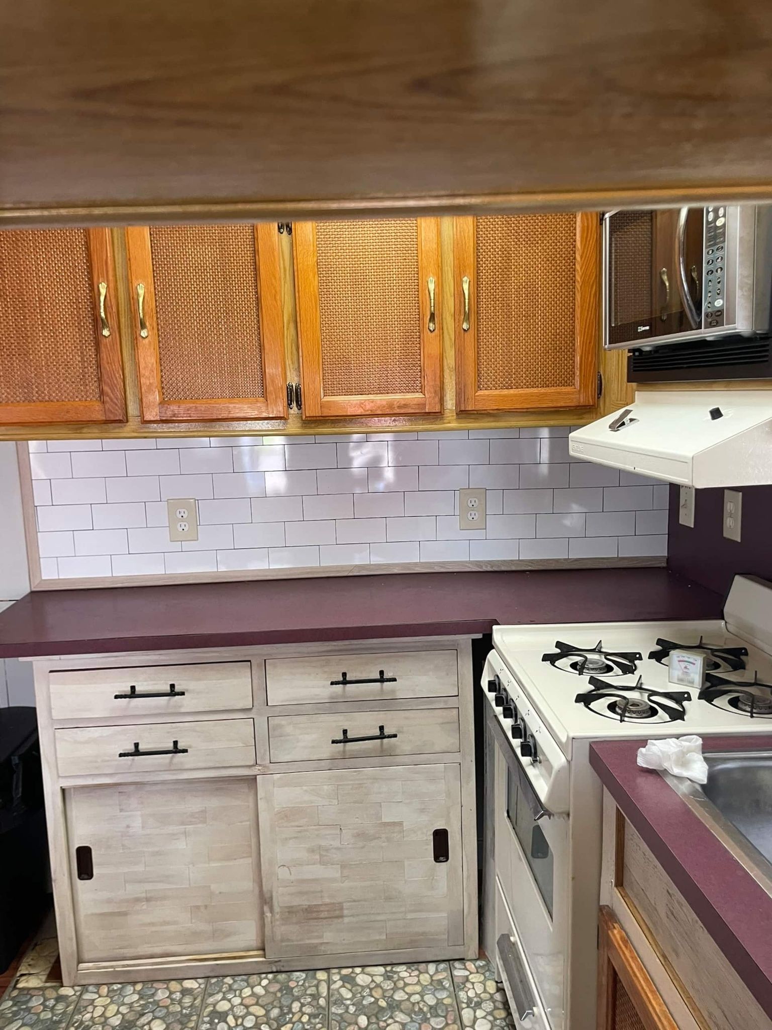 A compact kitchen with wooden cabinets, a gas stove, and a microwave.