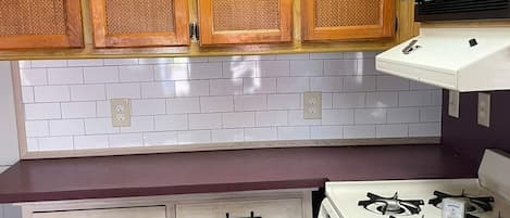 A compact kitchen with wooden cabinets, a gas stove, and a microwave.