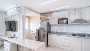Een moderne keuken met een ingebouwde magnetron, een koelkast van roestvrij staal en een granieten aanrecht.