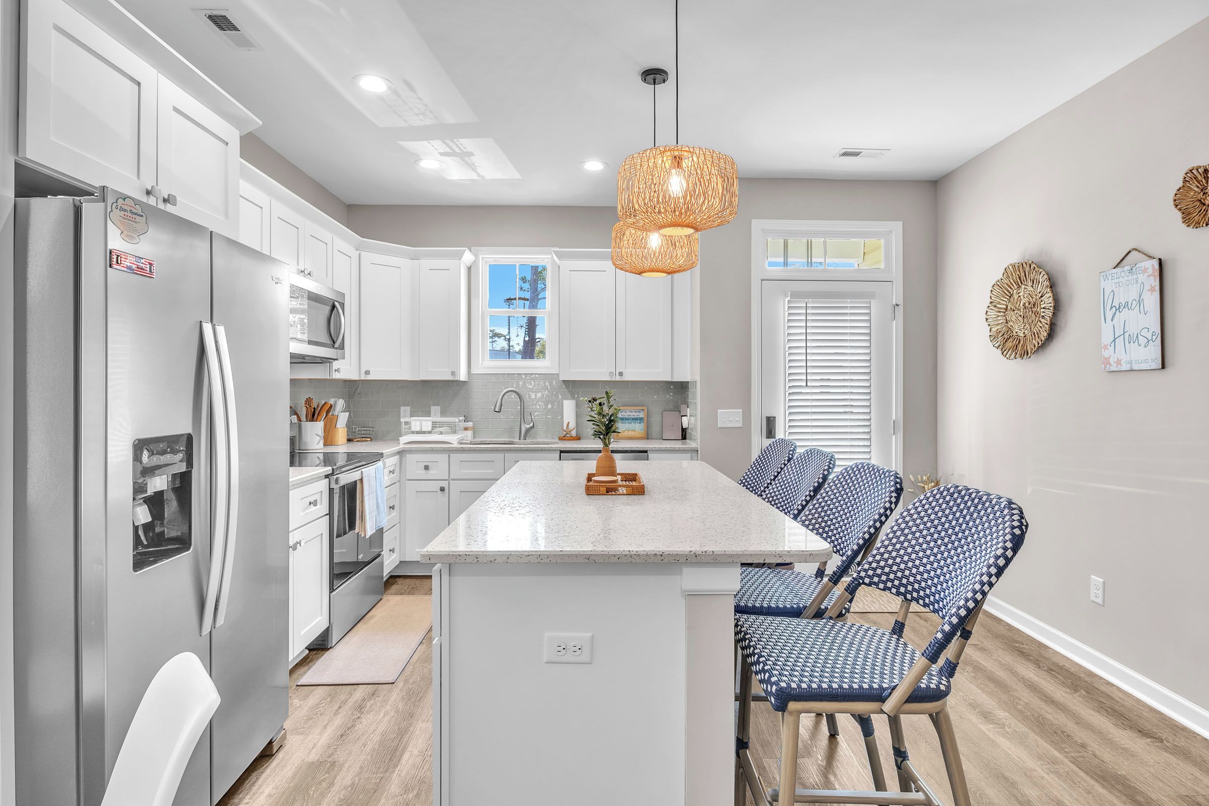 A modern kitchen with white cabinetry, a central island, and a hanging light fixture.