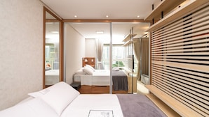 A modern hotel room with a large bed, a wooden wardrobe, and a view of the city through the window. - Flat in Full Condo, Setor Bueno - Txp0903 (Goiânia)