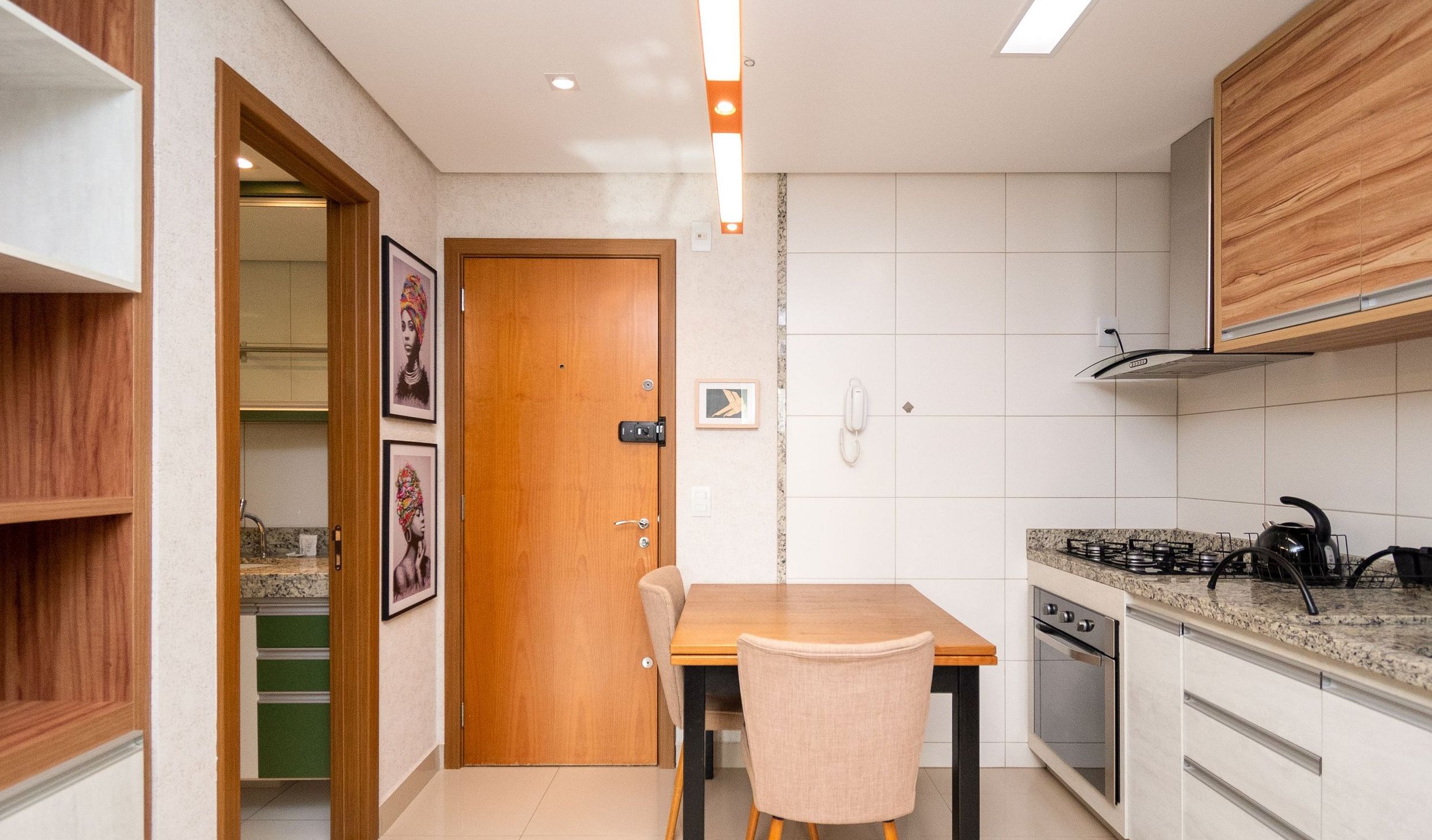 Een kleine keuken met een houten deur, een eettafeltje en een gasfornuis.