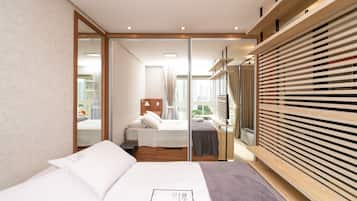 A modern hotel room with a large bed, a wooden wardrobe, and a view of the city through the window.