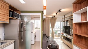 A modern kitchen with a built-in microwave, stainless steel refrigerator, and a washing machine in the adjacent room. - Flat in Full Condo, Setor Bueno - Txp0903 (Goiânia)