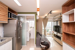 A modern kitchen with a built-in microwave, stainless steel refrigerator, and a washing machine in the adjacent room. - Flat in Full Condo, Setor Bueno - Txp0903 (Goiânia)