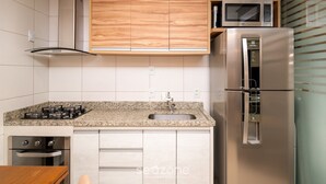 A kitchen with white cabinets, a stainless steel refrigerator, a microwave, and a gas stove. - Flat in Full Condo, Setor Bueno - Txp0903 (Goiânia)