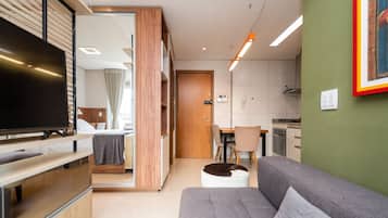 A modern living room with a flat-screen TV, a sofa, and a dining area with a table and chairs.