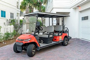 Un carrito de golf rojo estacionado en un camino de ladrillo.