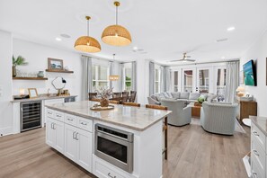 A modern kitchen with a central island, built-in appliances, and a dining area with a sofa and chairs.