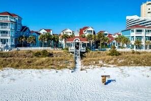 A beachfront hotel with a central pavilion, multiple-story buildings, and a sandy beach in the foreground.