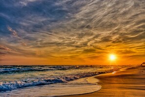 Ein Strand mit Wellen und einem Sonnenuntergang.